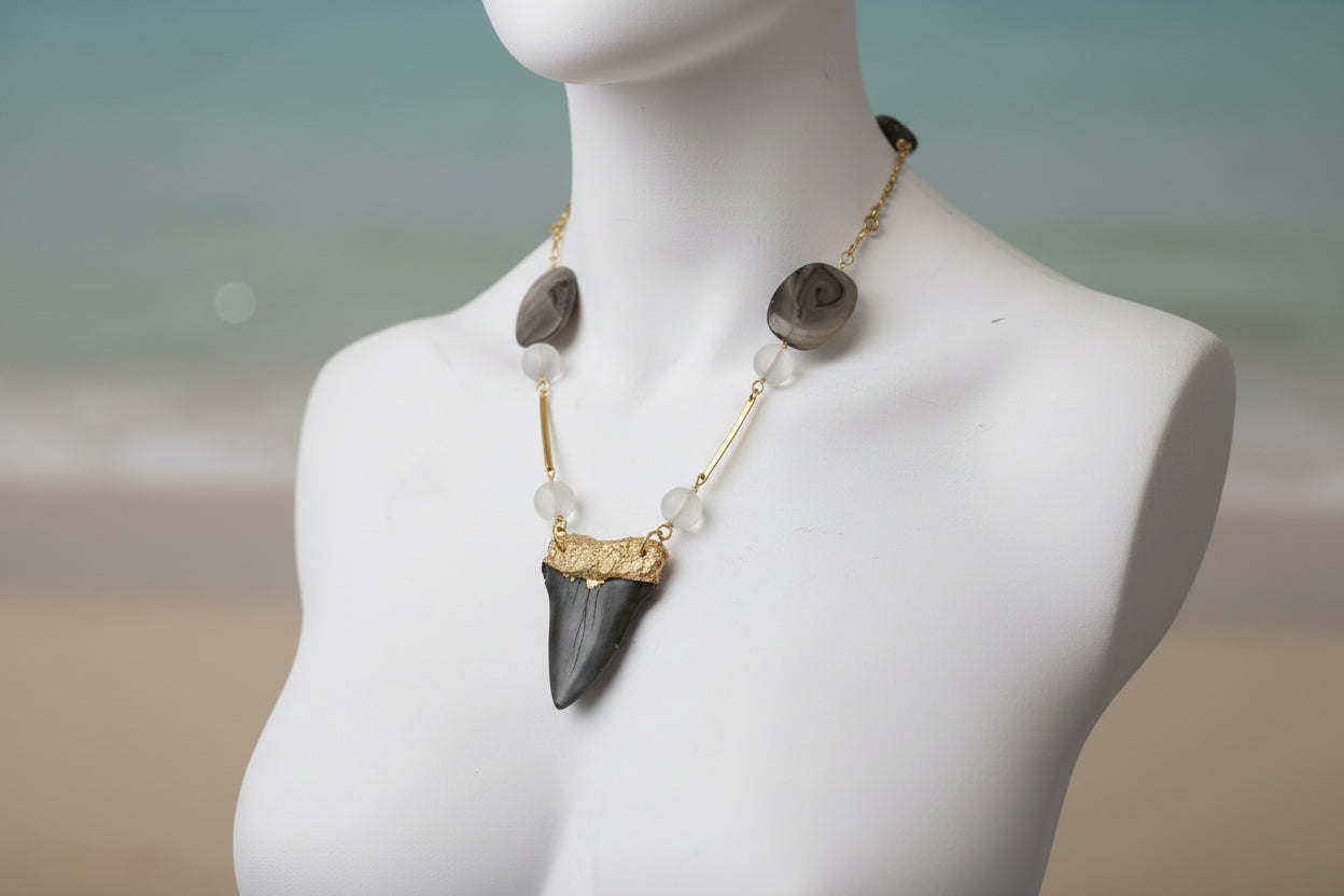 Necklace with a large dark stone pendant on a mannequin against a gray background