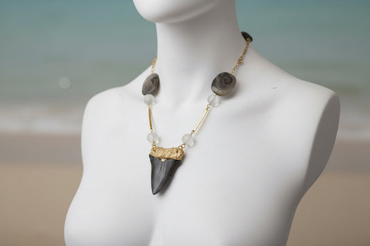 Necklace with a large dark stone pendant on a mannequin against a gray background